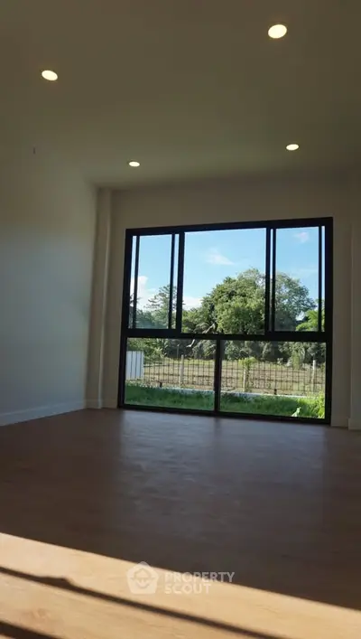 Spacious room with large window offering scenic outdoor view, perfect for natural light lovers.