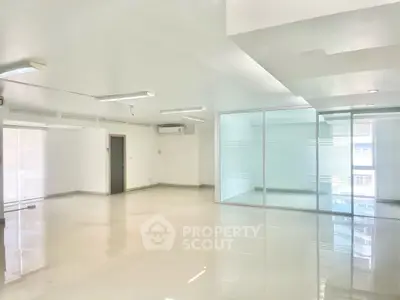 Spacious modern office space with glass partitions and ample lighting.