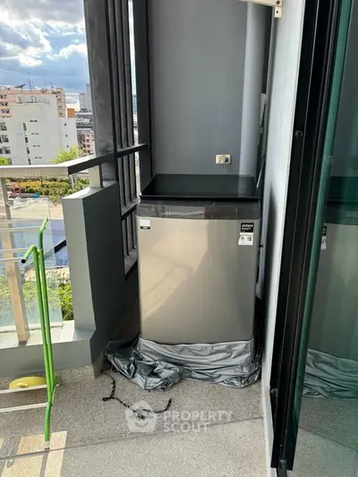 Modern balcony with compact fridge and city view, perfect for urban living.