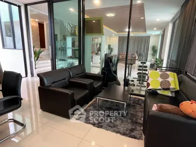Luxurious modern living room with sleek black leather furniture and glass partitions in a spacious open layout.