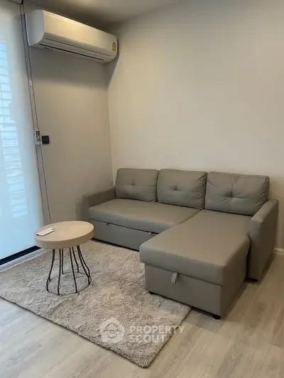 Modern living room with sleek gray sofa and stylish round coffee table, featuring a cozy ambiance.