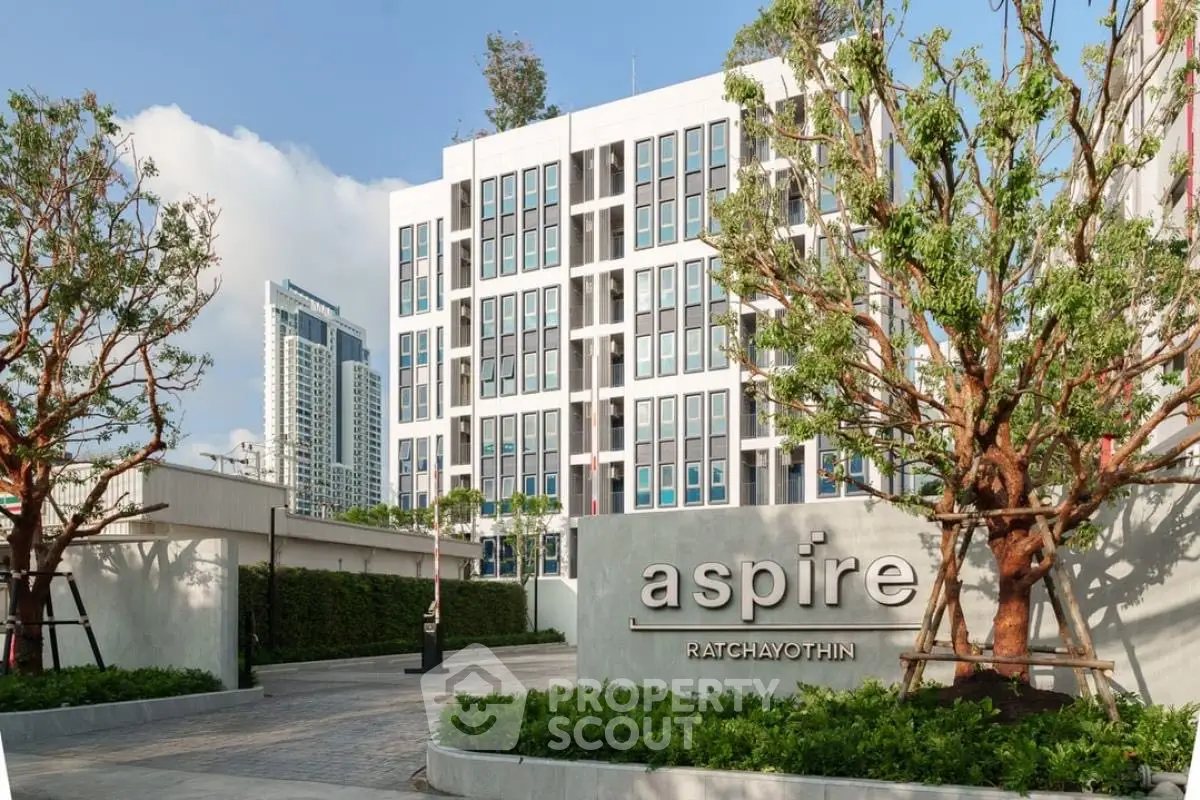 Modern apartment building with lush landscaping at Aspire Ratchayothin.