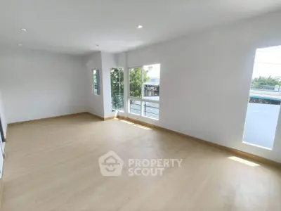Spacious and bright empty room with large windows and wooden flooring