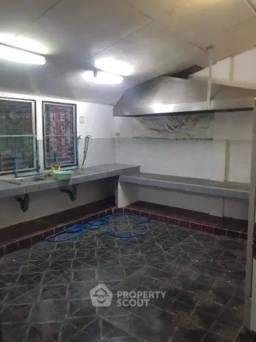 Spacious kitchen with industrial-style countertops and tiled flooring, ideal for culinary enthusiasts.