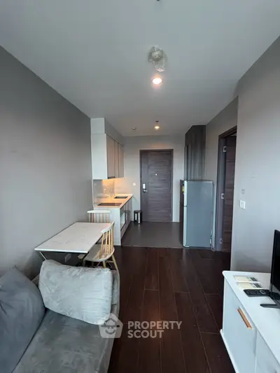 Modern apartment interior with open kitchen and cozy living area, featuring sleek design and natural light.