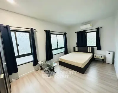 Spacious bedroom with modern decor and large windows for natural light