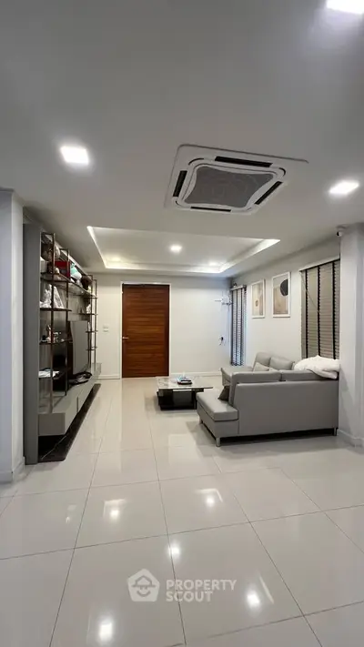 Modern living room with sleek furniture and stylish decor, featuring a cozy gray sofa and elegant shelving.