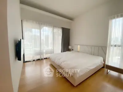 Spacious modern bedroom with large windows and city view, featuring elegant minimalist design and natural light.