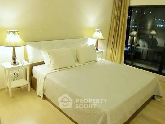 Elegant bedroom with cozy lighting and large window offering city views, perfect for relaxation.