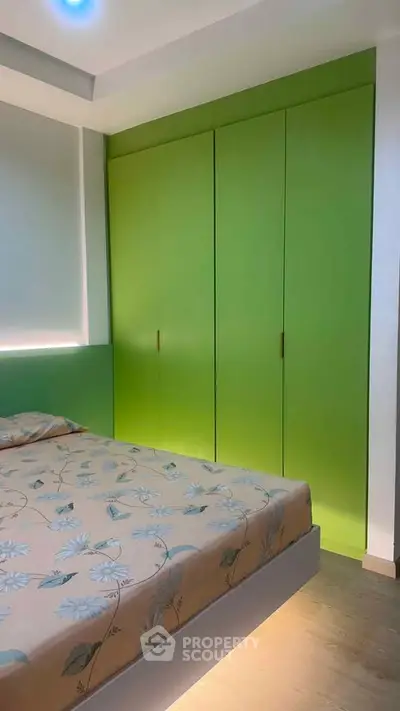 Modern bedroom with vibrant green wardrobe and floral bedding