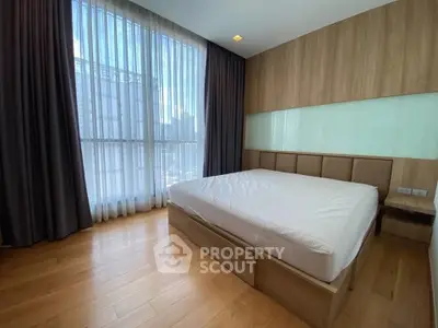 Spacious bedroom with large window and wooden flooring in modern apartment
