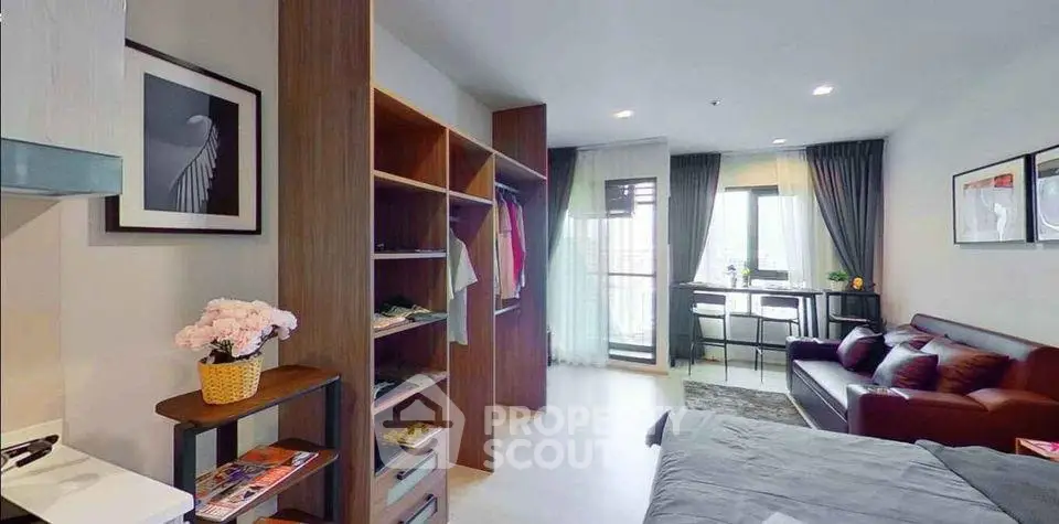 Modern studio apartment with open layout, stylish decor, and natural light from large windows.