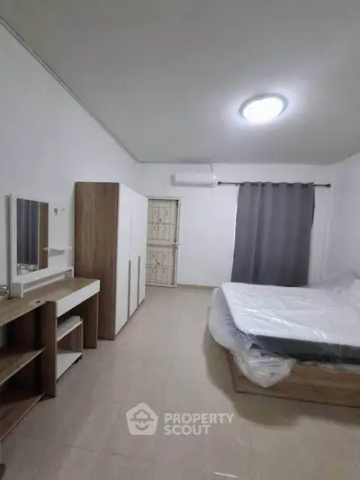Spacious bedroom with modern furniture and natural light, perfect for comfort and relaxation.