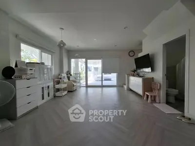 Spacious living room with modern decor and large windows leading to a balcony.