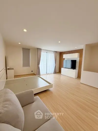 Spacious modern living room with wooden flooring and large windows for natural light.