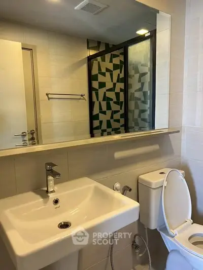 Modern bathroom with stylish geometric shower tiles and sleek fixtures.