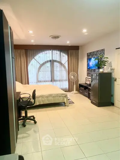 Spacious bedroom with modern decor and large window for natural light.