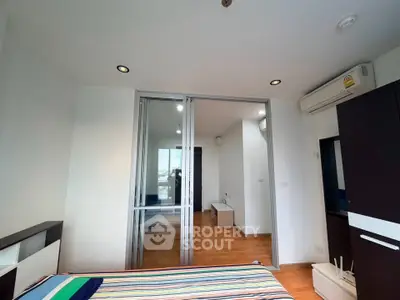 Modern bedroom with sliding glass doors and wooden flooring in a stylish apartment.
