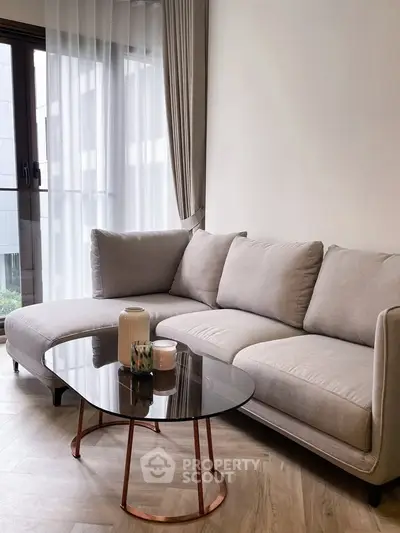Elegant living room with modern gray sofa and stylish glass coffee table.