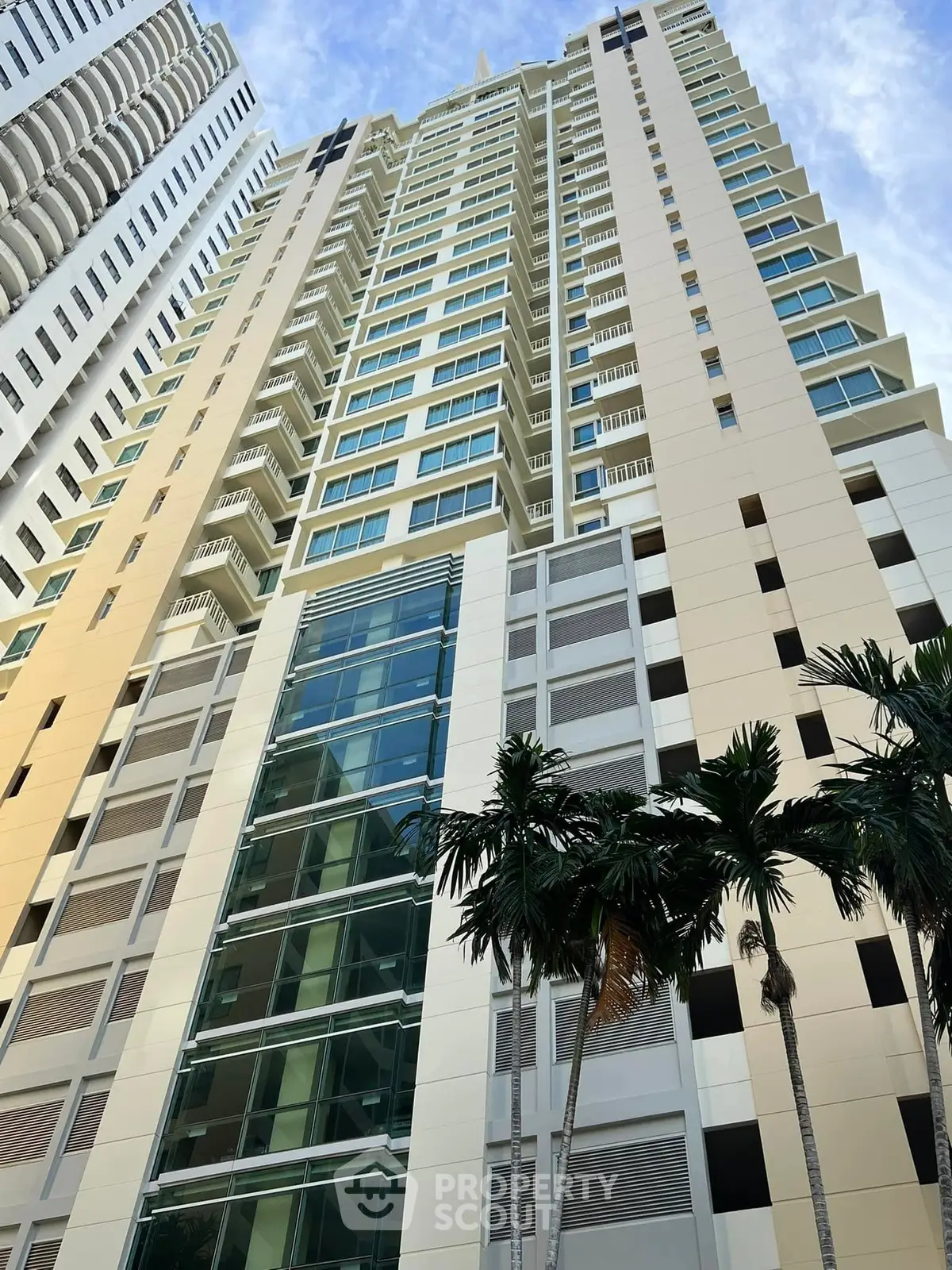 Stunning high-rise building with modern architecture and palm trees, perfect for urban living.