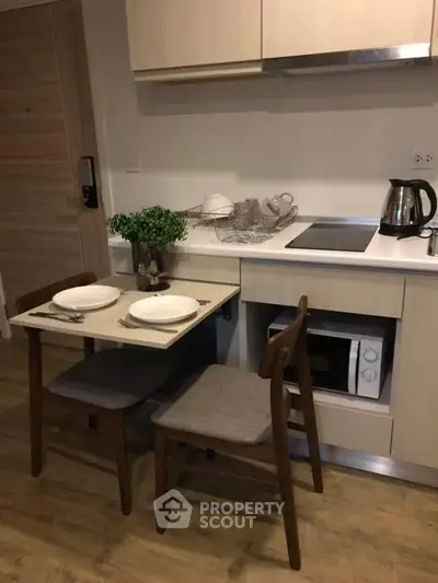 Cozy kitchen with compact dining area, modern appliances, and stylish wooden furniture.
