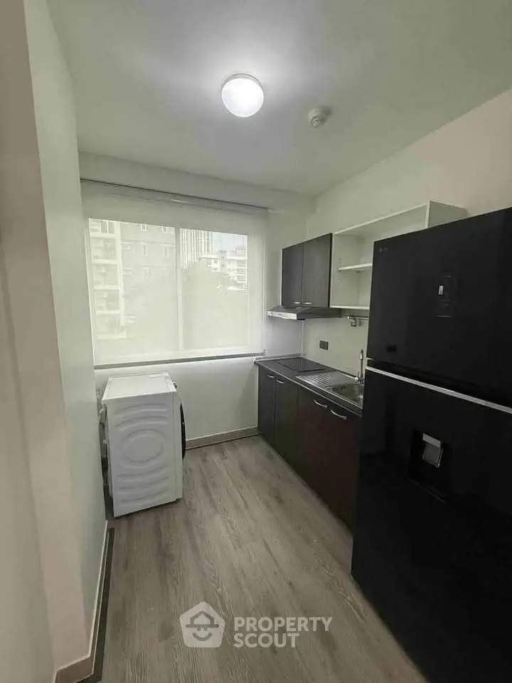 Modern kitchen with sleek black appliances and large window offering natural light.