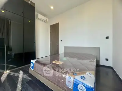 Modern bedroom with sleek black wardrobe and air conditioning in a minimalist design.