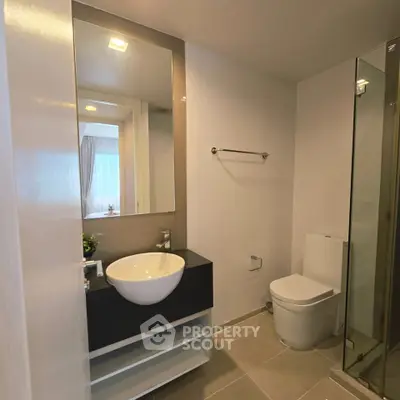 Modern bathroom with sleek fixtures and glass shower in contemporary apartment.
