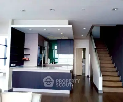 Modern open-layout kitchen with sleek design and wooden staircase