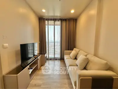 Modern living room with cozy sofa and flat-screen TV, featuring floor-to-ceiling windows and elegant curtains.