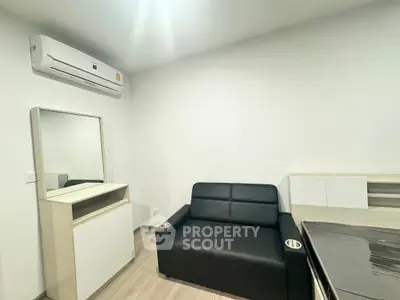 Modern living room with sleek black sofa and air conditioning in a minimalist apartment.