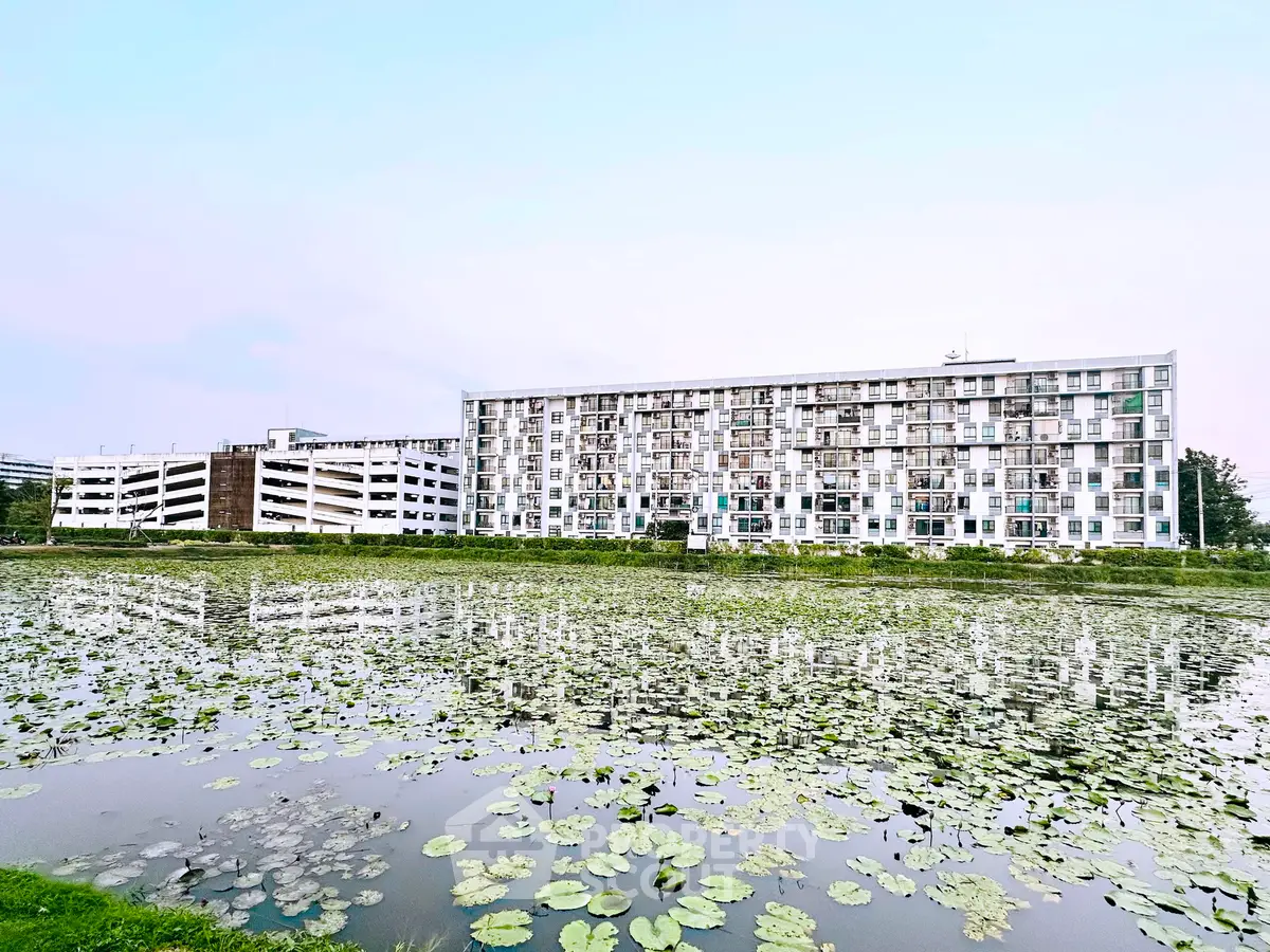 Modern apartment building with serene pond view and lush greenery