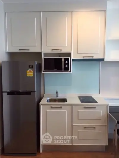 Modern compact kitchen with sleek cabinetry and stainless steel fridge