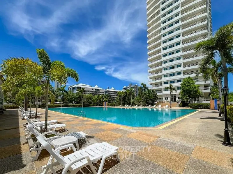 Luxurious high-rise building with a stunning outdoor pool and sun loungers, perfect for relaxation.