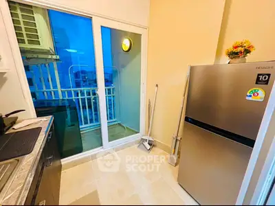Modern kitchen with stainless steel fridge and balcony access, perfect for urban living.