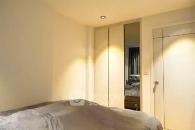 Cozy bedroom with warm lighting, built-in wardrobes, and a large bed, perfect for restful nights in a modern home.