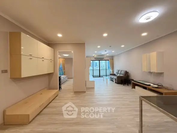 Spacious modern living room with balcony and city view, featuring sleek furniture and elegant lighting.