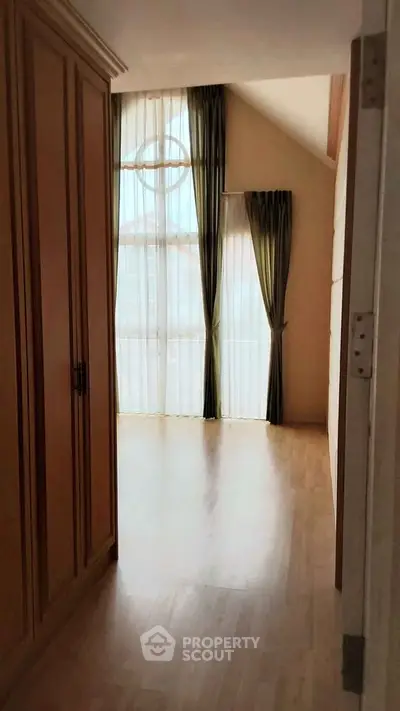 Spacious bedroom with large windows and elegant curtains, perfect for natural light lovers.