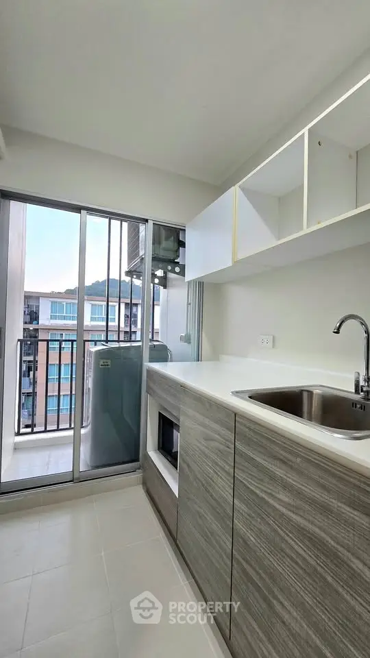 Modern kitchen with sleek cabinetry and balcony view in urban apartment