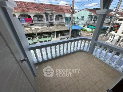 Charming balcony with classic railing offering vibrant street view in a lively neighborhood.