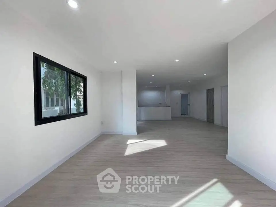 Spacious open-plan living area with modern flooring and large window, ideal for natural light.