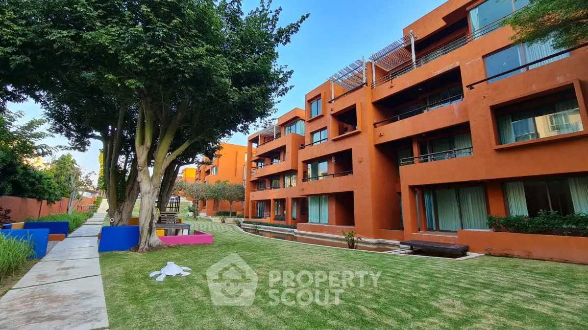 Modern apartment complex with vibrant orange facade and lush green garden