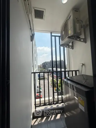 Compact balcony with city view, featuring air conditioning unit and washing machine, ideal for urban living.
