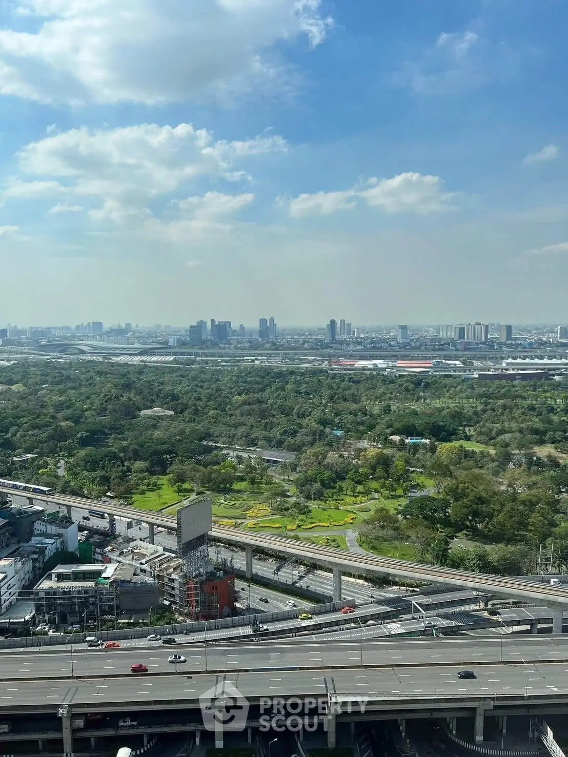Stunning cityscape view from high-rise building with lush greenery and urban skyline.