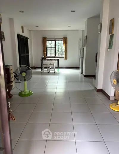 Spacious open-plan living area with tiled flooring and natural light, ideal for modern living.