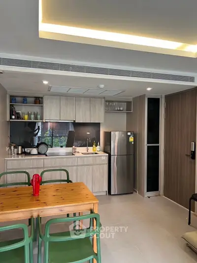 Modern kitchen with open layout and dining area, featuring stainless steel appliances and wooden cabinetry.