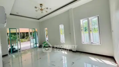 Spacious living room with large windows and elegant chandelier, offering a bright and airy atmosphere.