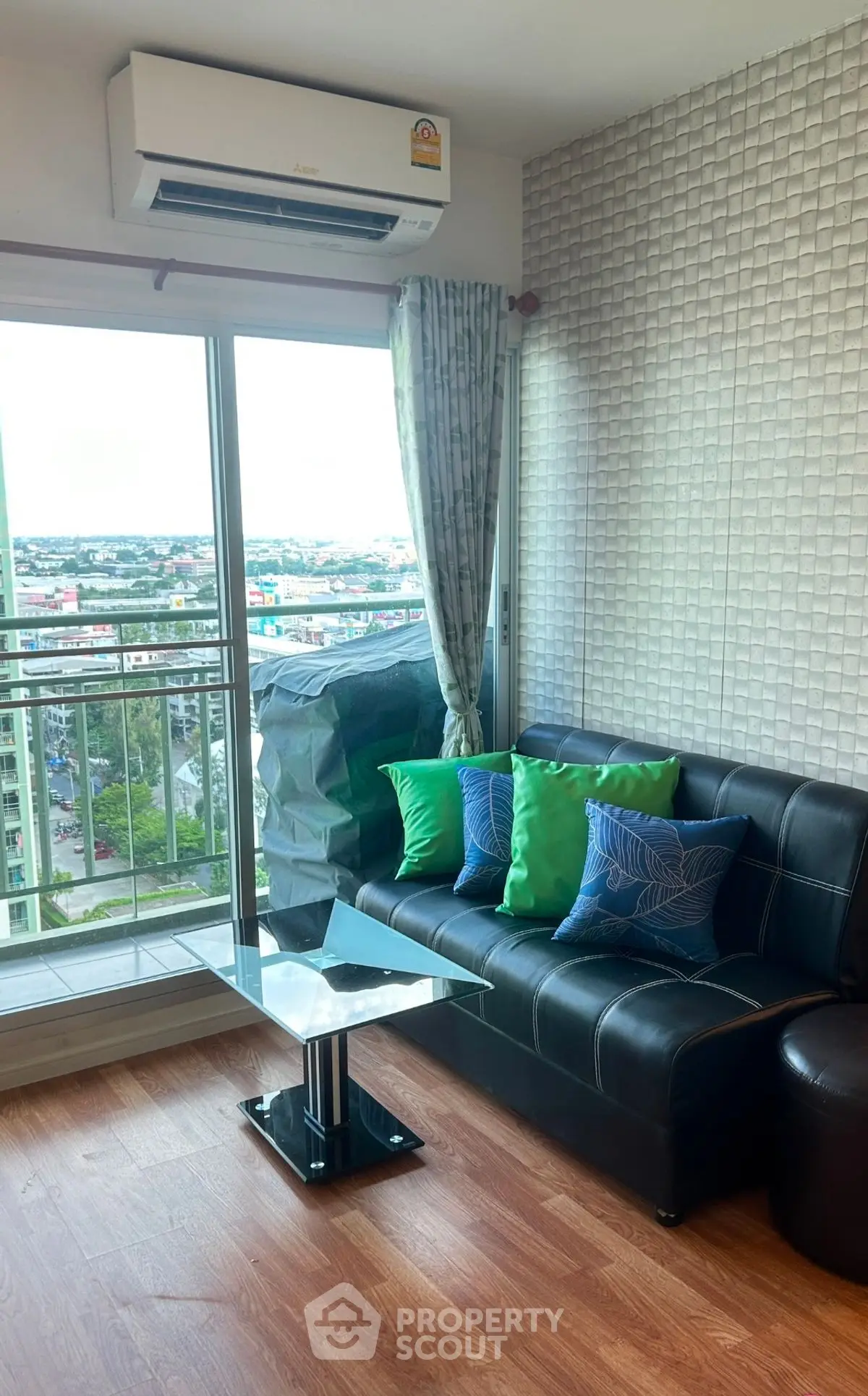 Modern living room with city view, featuring stylish leather sofa and vibrant cushions, perfect for urban living.