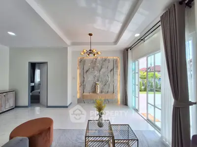 Elegant living room with modern chandelier and large windows opening to garden view.