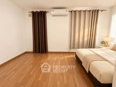 Spacious bedroom with wooden flooring and modern decor in a cozy apartment.